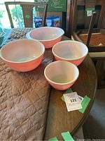 Four peach luster Pyrex mixing bowls arranged on table