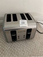 Front side view of KitchenAid 4-slice toaster showing control levers, buttons, and stainless steel finish