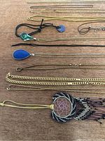 Detailed image showing mixed materials including cords, glass-like pendants, and thin delicate chains.
