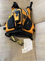 Full view of orange and black Kokatat PFD with attached safety whistle and Wenoka knife box