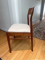 Side view of teak dining chair showing frame and upholstered seat