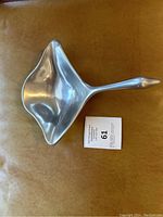 Photo of the goose sculpture showing the side profile and wing shape, placed on a brown leather surface with auction lot card.