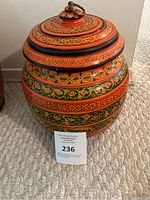 Full view of the wooden lidded box showing vibrant colors and floral bands in orange, green, yellow, and black.