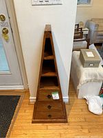 Front view showing pyramid shape, three drawers with metal ring pulls, and three open shelves