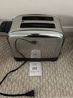 Front angle showing two bread slots, cord, and reflective stainless steel body