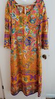 Front view of the vibrant multicolor floral silk dress hanging on door, showing 3/4 sleeves and knee-length design.