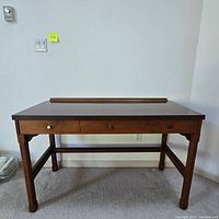 Front view of handmade wooden desk showing two front drawers with wooden knobs, wood-grain laminate top, and sturdy four legs with horizontal stretcher bars.