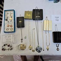Full lot showing pendant necklaces, clip-on earrings, bracelet, ring holder on cloth background.