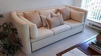 Front view of cream upholstered sofa showing frame, arms, and cushion arrangement
