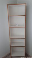 Full front view of the tall white laminate bookcase with beige trim, showing all 5 shelves empty.
