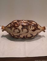 Side view of vintage 1960s Jean Cartier Canadian clay fish baker cocotte showcasing painted fish design and spouted handles