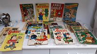 Lot of approximately 19 vintage comic books arranged on surface showing front covers including Tom and Jerry, Uncle Scrooge, Annie Oakley, Andy Panda, Angel, Little Lulu, and others