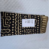 Folded mud cloth showing contrasting black and beige pattern with geometric designs and symbols.