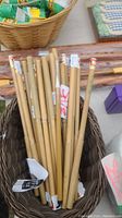Basket containing approximately 14 bamboo-handled art brushes with varied brush tips and price tags.