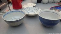 Three basic chinaware bowls placed on a grey surface, showing the inside decorative patterns.