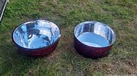 Photo of two bowls placed on grass showing their shiny metallic interiors and red textured exteriors.