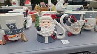 Photo showing a row of holiday mugs featuring Santa Claus and snowmen, each with unique details and festive decoration.