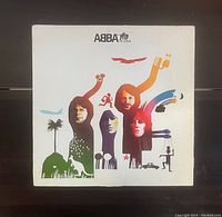 Front cover of the ABBA 'The Album' vinyl record showing artistic stylized portraits of the band members with colorful graphic design elements on a white background.