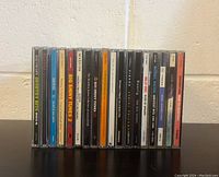 Front-facing photo of the 16 assorted CDs showing titles and artists in jewel cases arranged side by side.