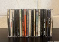 Front view of 14 compact discs in jewel cases arranged side by side, showing spine labels and titles.