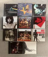 Photo of 11 rock CDs including Pink Floyd, KISS, Bruce Springsteen, Eric Clapton and others.