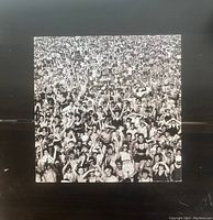 Photo of the vinyl record cover featuring a black and white crowded scene of people at a beach or event.