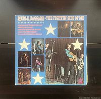 Front cover of Merle Haggard's vinyl record 'The Fightin' Side Of Me' showing a blue cover with white stars and photos of band members on stage.