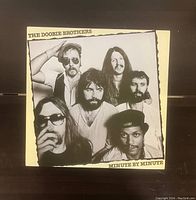Front cover of The Doobie Brothers Minute By Minute vinyl album with band photo.
