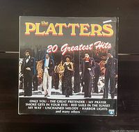 Front of vinyl record album cover titled 'The Platters 20 Greatest Hits', featuring band members and a list of hit songs.