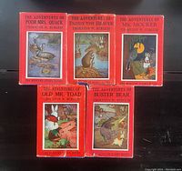 Five vintage Thornton W. Burgess bedtime story books with red covers and illustrated animal characters on the covers, arranged on a dark surface.
