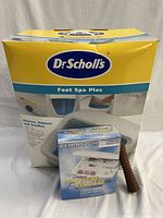 Photo showing Dr. Scholl's Foot Spa Plus in original box, Remington manicure pedicure kit, and wooden massage roller together.