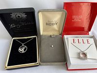 Three boxed items: Lady Harris sterling silver necklace, Koby stud with clear stone, ELLE sterling silver necklace marked genuine ruby