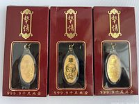 Set of three Chinese Zodiac golden keychains in maroon presentation boxes with clear window showing each keychain inside, featuring Ram, Monkey, and Horse Zodiac signs.