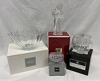 Four boxed crystal pieces including Mikasa and Royal Doulton brands arranged on boxes, showing bowl, figurine, trinket dish, and vase.