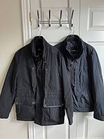 Two black Hugo Boss jackets hanging on a double hook rack, showing front view and size comparison