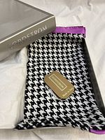 Silver Nordstrom box with silk scarf partially visible inside showing houndstooth black and white pattern and purple-pink edge with attached Nordstrom Made in Italy tag.