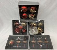 Six boxed sets of mouth blown glass Christmas ornaments in red and gold, showing overall variety and packaging