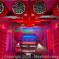Photo of a vehicle inside the Popular Car Wash showing the car wash equipment in use, including bright red finishing touches with automated brushes and spray mechanisms.