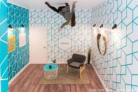 Photo of an upside-down room illusion with a woman posed on the ceiling.