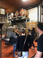 Group of guests inside a winery barrel room with wine-making equipment