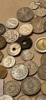 Close-up of assorted world coins showing different ranks and historic designs including coins with holes and various metal colors.