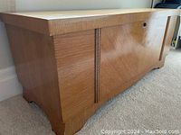Side view of the closed wooden cedar chest showing exterior finish and decorative trim.
