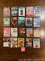 Photo shows 20 DVD cases arranged on wooden floor including titles from Barbie, Indiana Jones, Hunger Games, Star Trek, and more.