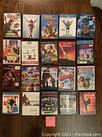 Photo showing 20 DVD cases arranged in a 4x5 grid, featuring a variety of movie titles including family movies, animated films, documentaries, and music specials.