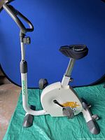 Photo of the Tunturi exercise bike showing white frame, adjustable seat with Bell memory foam cover, and pedals.