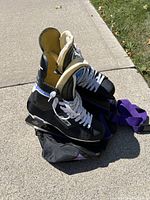 Photo of Bauer Supreme Custom 4000 black men's hockey skates size 9.5 sitting on bag outdoors on cement with grass around, showing skate side, open top, white laces.