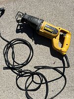 Top view of DeWalt reciprocating saw showing overall condition and attached power cord on concrete.