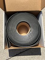 Top view of the black vinyl wall base coil inside box showing flexible rolled material.