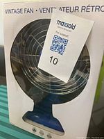 Front view of the boxed vintage style portable fan showing blue fan and metal grille.