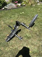 Full view of the black metal and plastic vehicle bike rack placed on grass, showing structure and bike cradles.